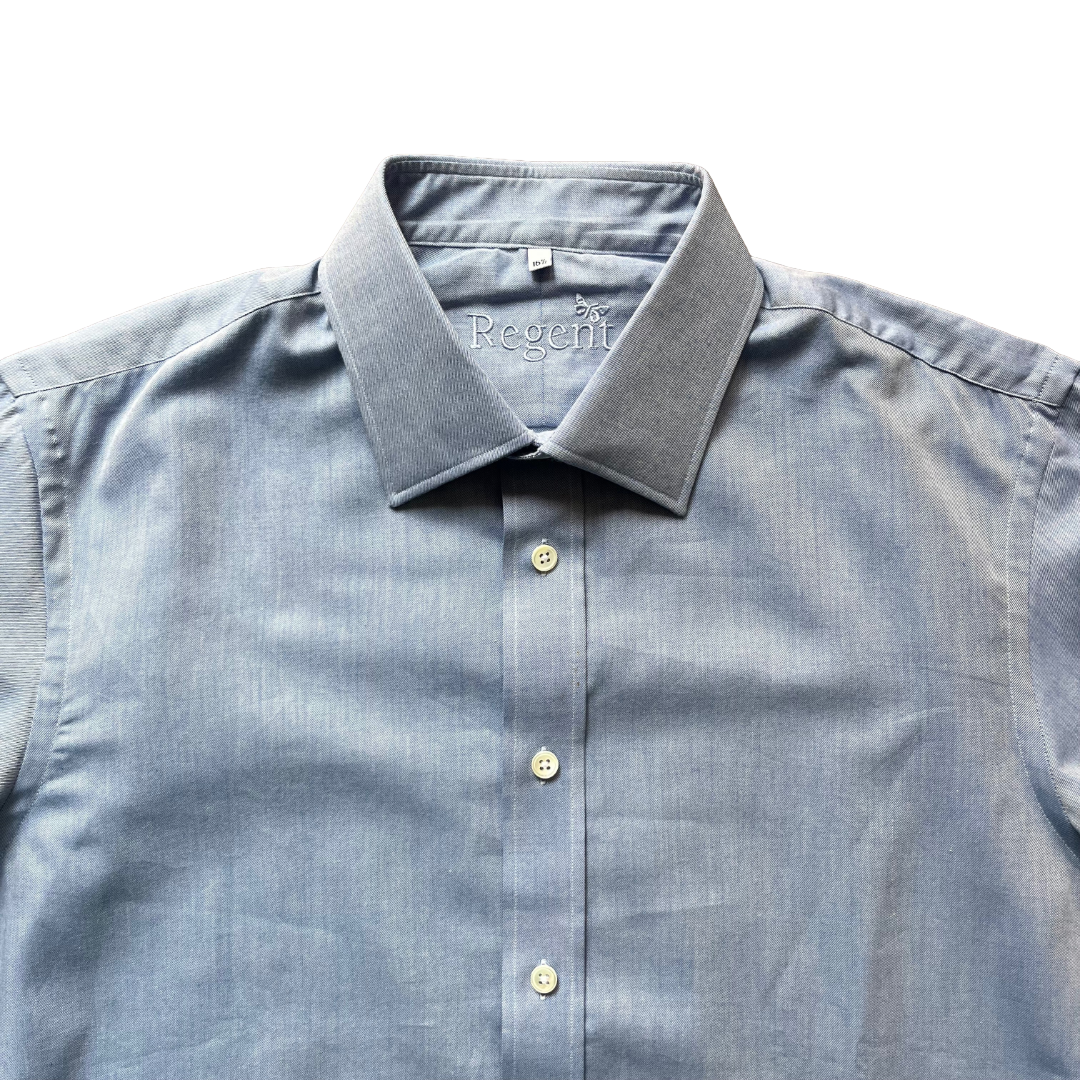 A close-up of a light blue chambray button-down shirt with a spread collar, showing the 'Regeffi' brand name embroidered inside the collar, set against a plain white background.