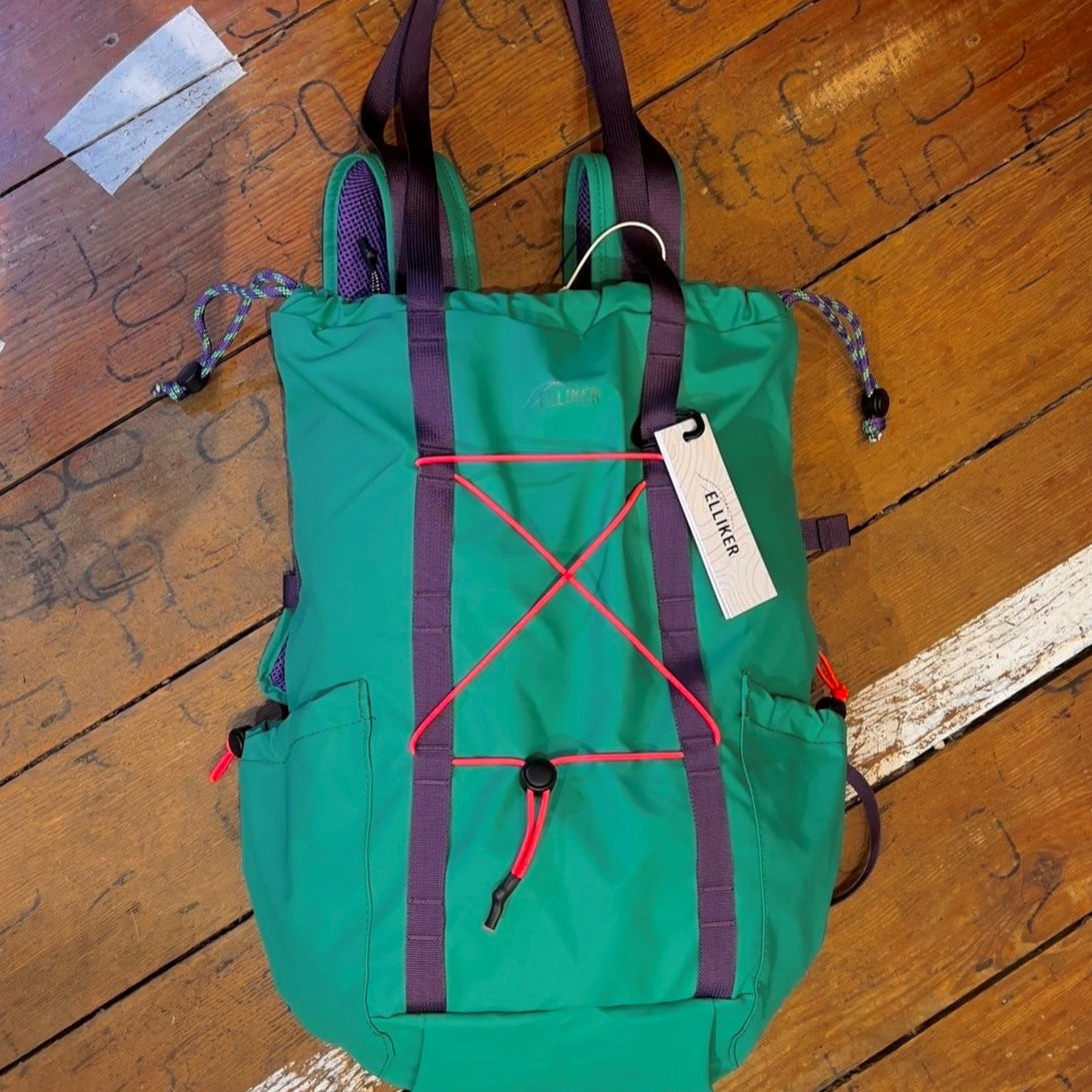 Green bag with purple straps with additional handles for carrying as a tote. 