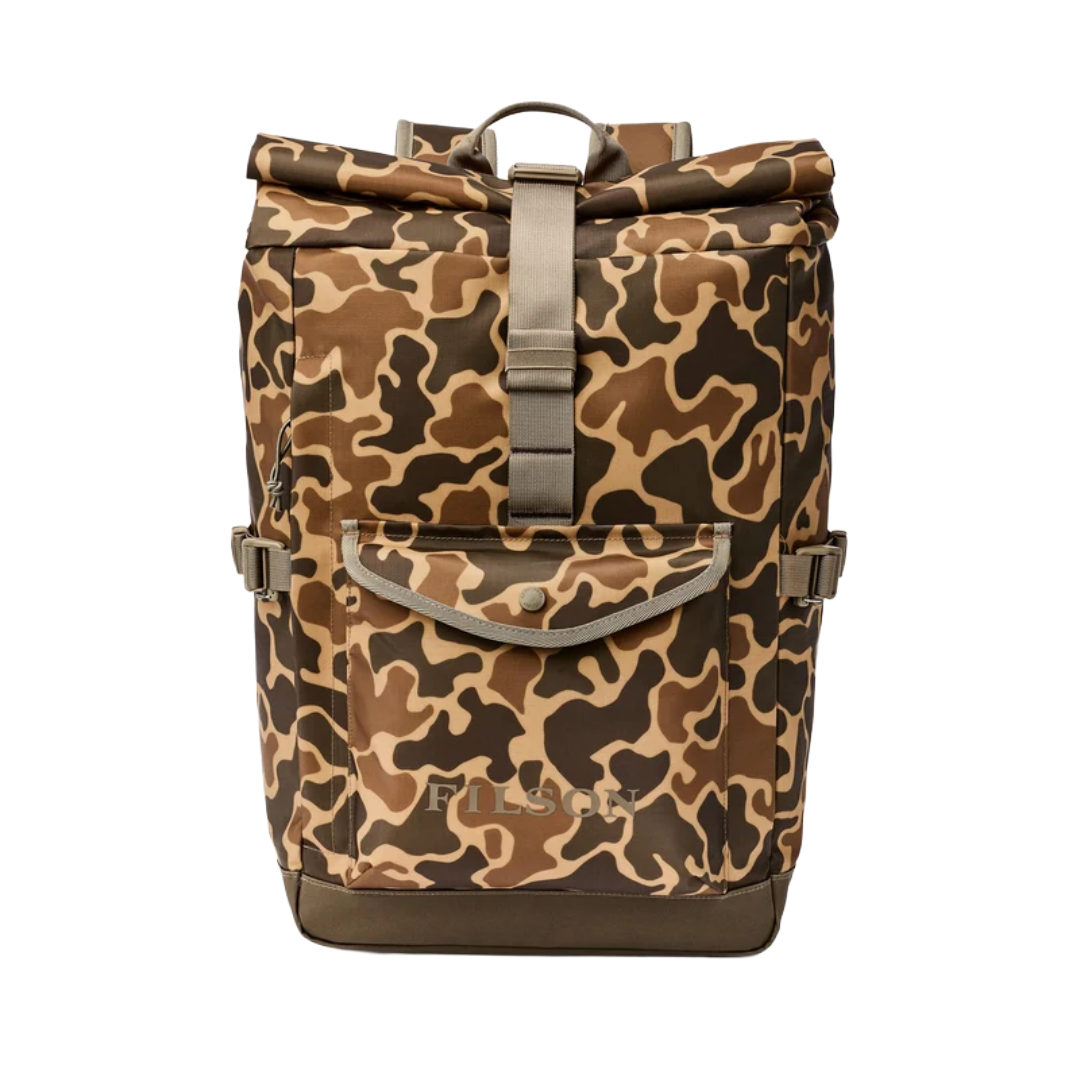 A roll-top backpack in a brown, beige, and black camouflage pattern, featuring a front utility pocket with a snap button and a central vertical strap closure, shown against a plain white background.