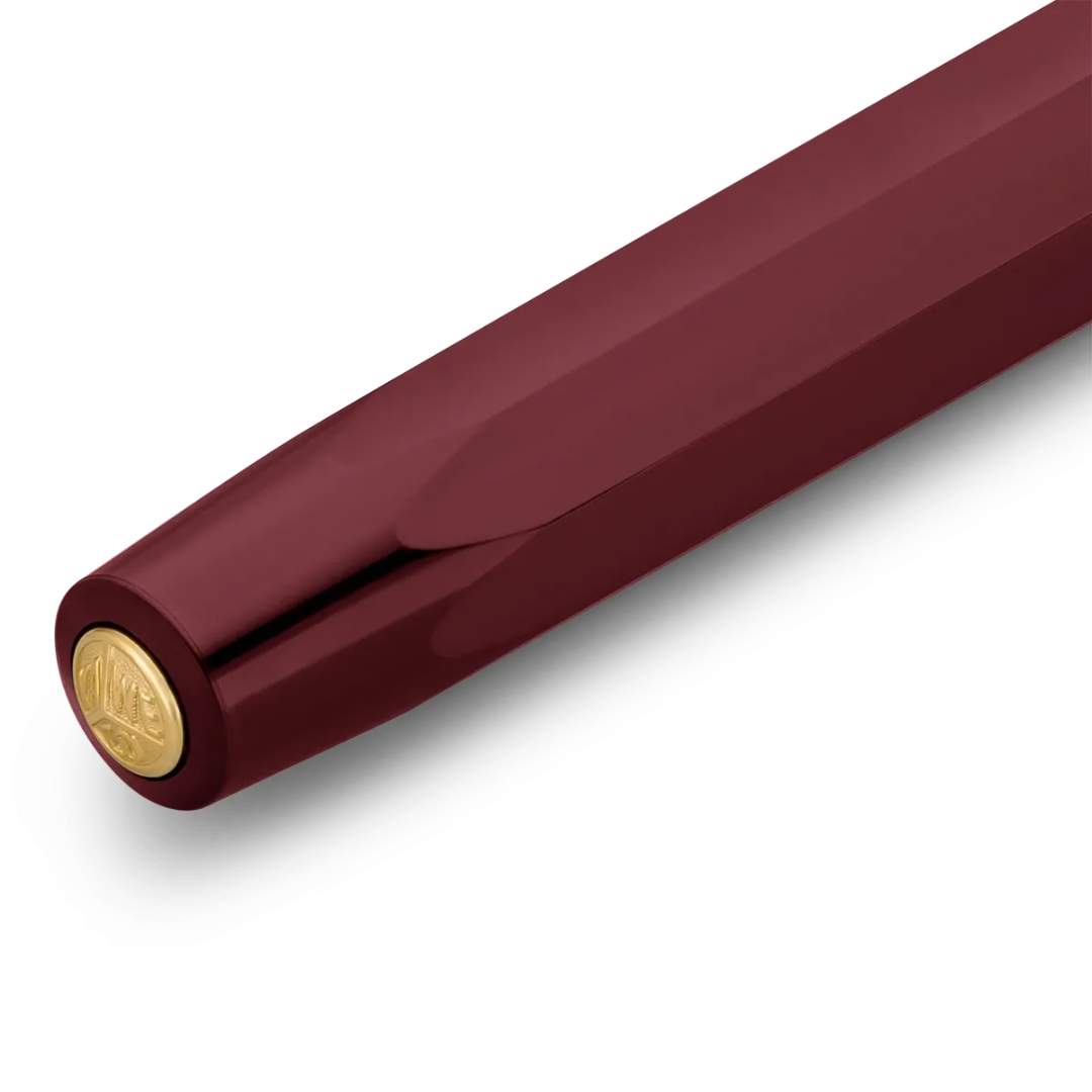A close-up of a luxury pen featuring a deep burgundy barrel and a polished gold-tone end cap with an embossed logo, set against a clean white background.
