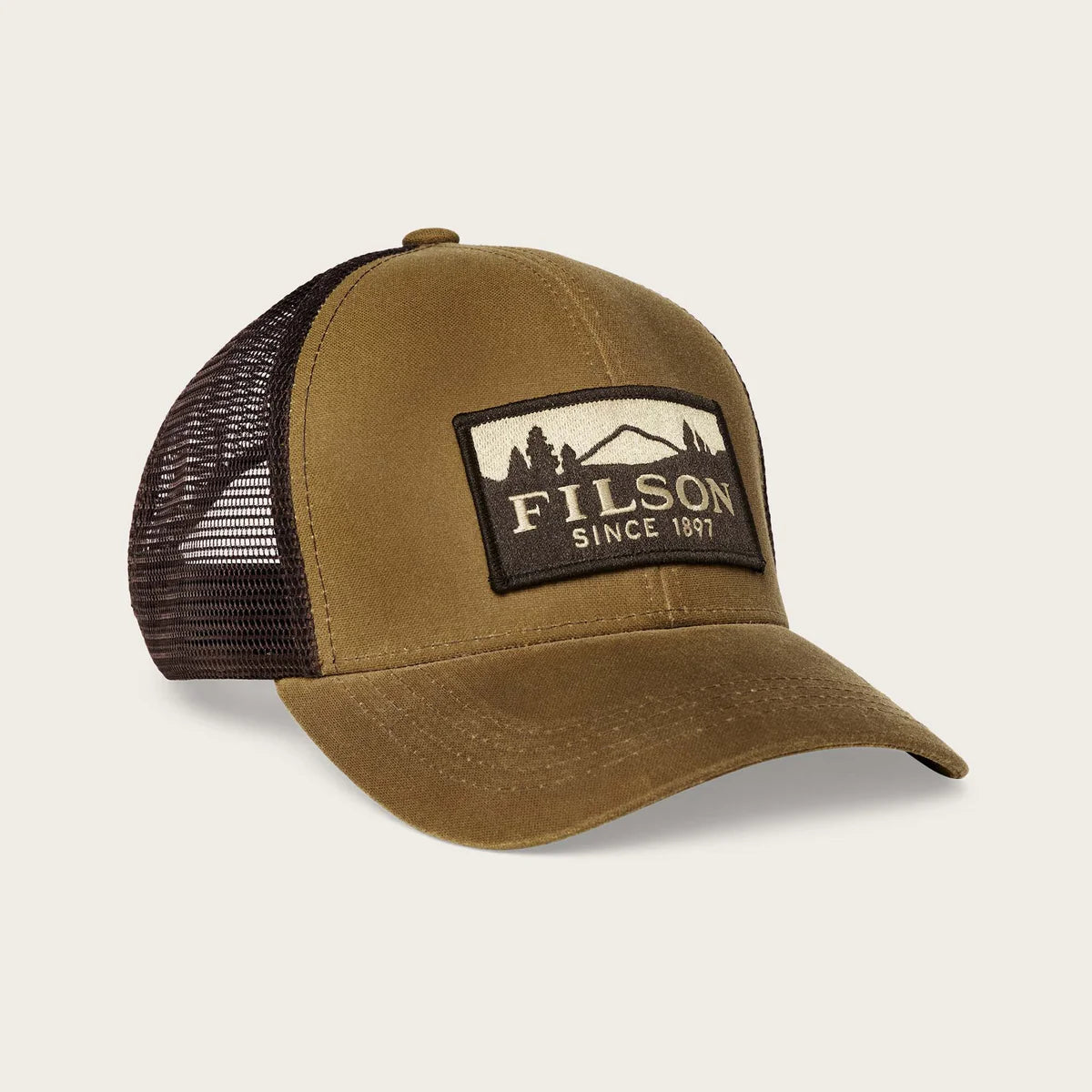 Brown trucker cap with black mesh and Filson logo on a beige background