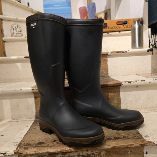 Pair of black rubber boots on a wooden platform with a store interior background.