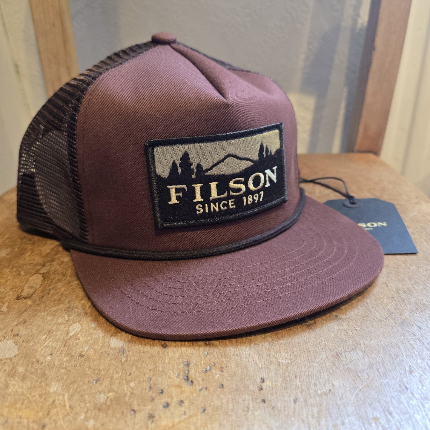 Brown Filson cap on a wooden surface with a blurred background