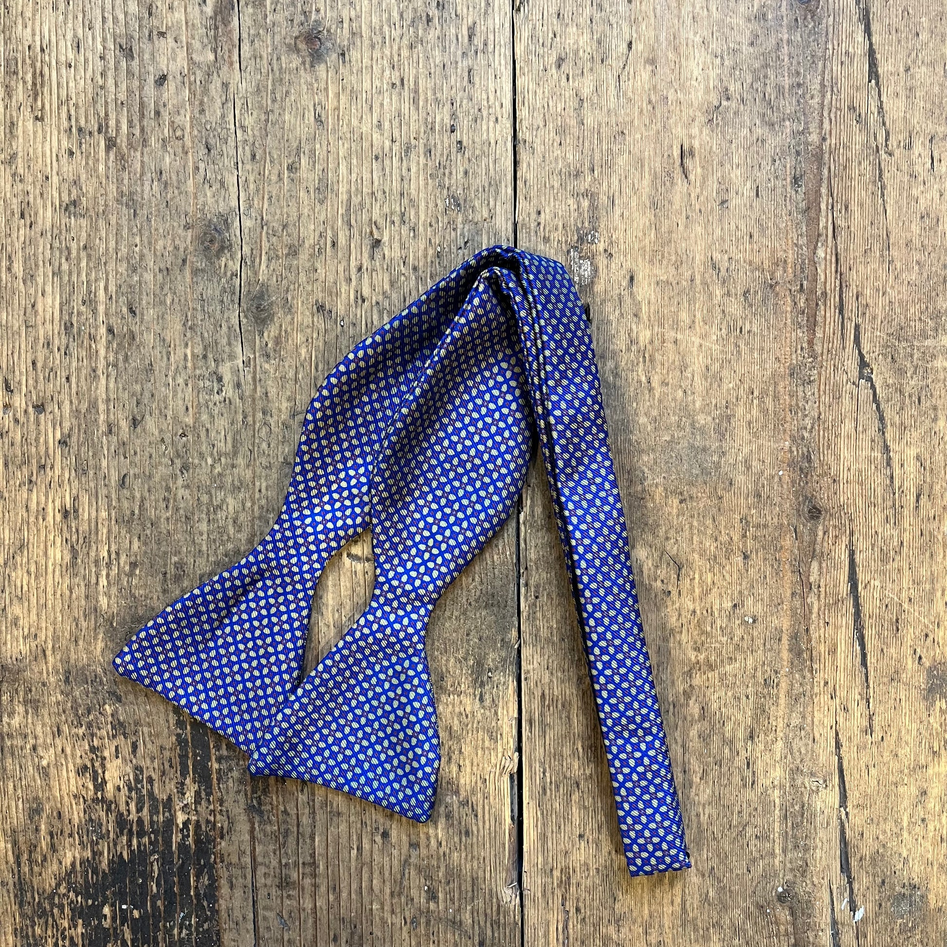 Blue bow tie with Geometric Floral Pattern, in yellow, blue and maroon.
Sold at Regent Tailoring Salisbury