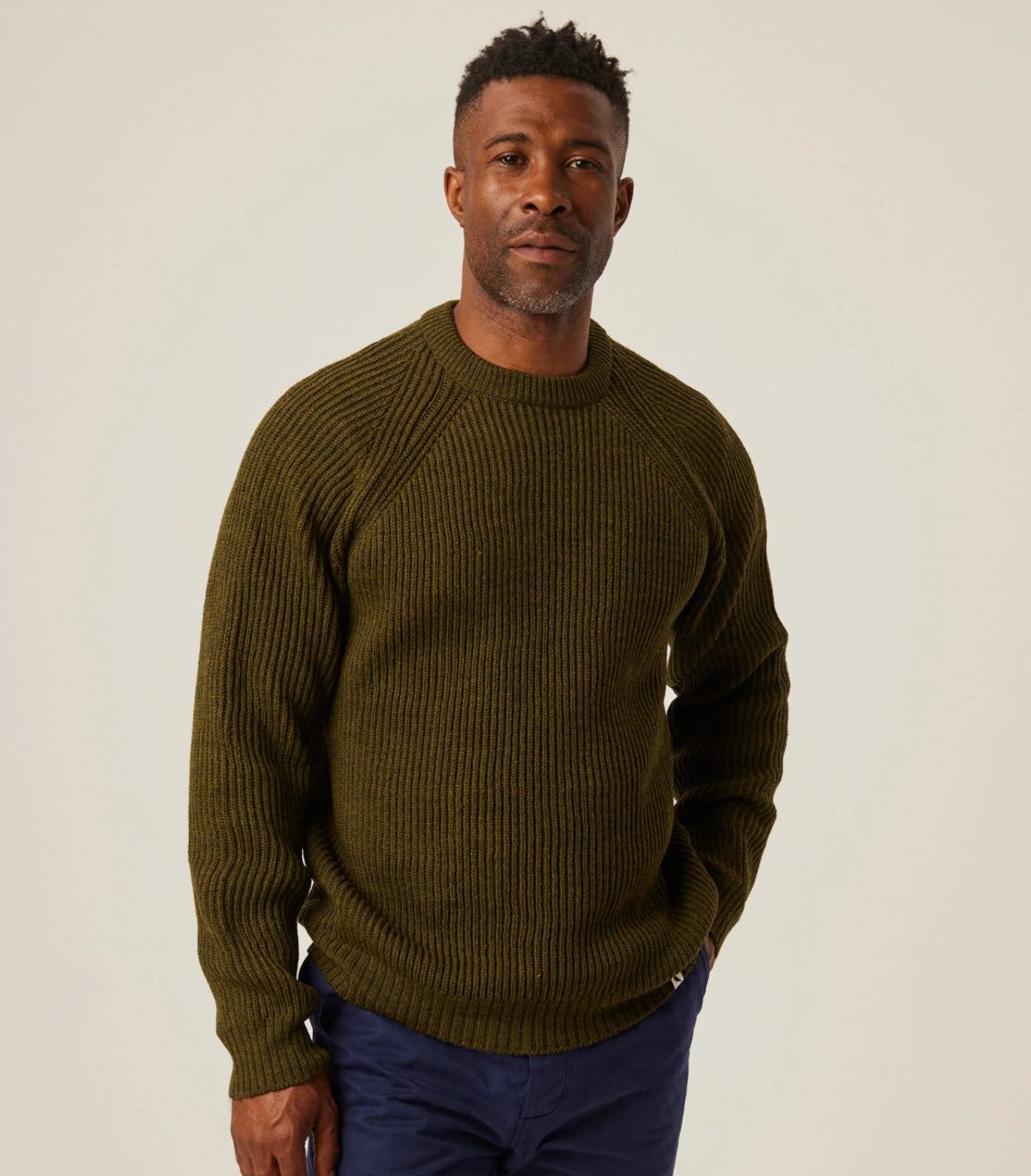 Man wearing a green sweater against a plain background