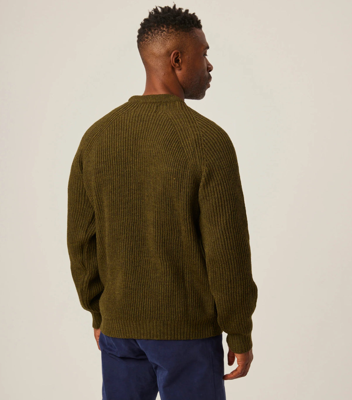 Man wearing a green sweater against a plain background