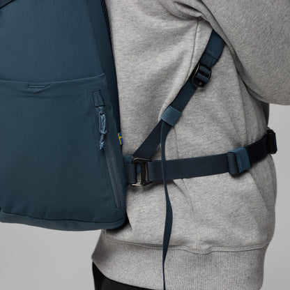 Person wearing a gray hoodie with a navy backpack on a light gray background