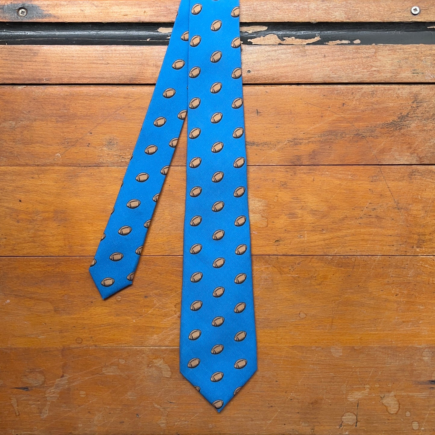 Blue regent tie made from woven wool with rugby ball print pattern
