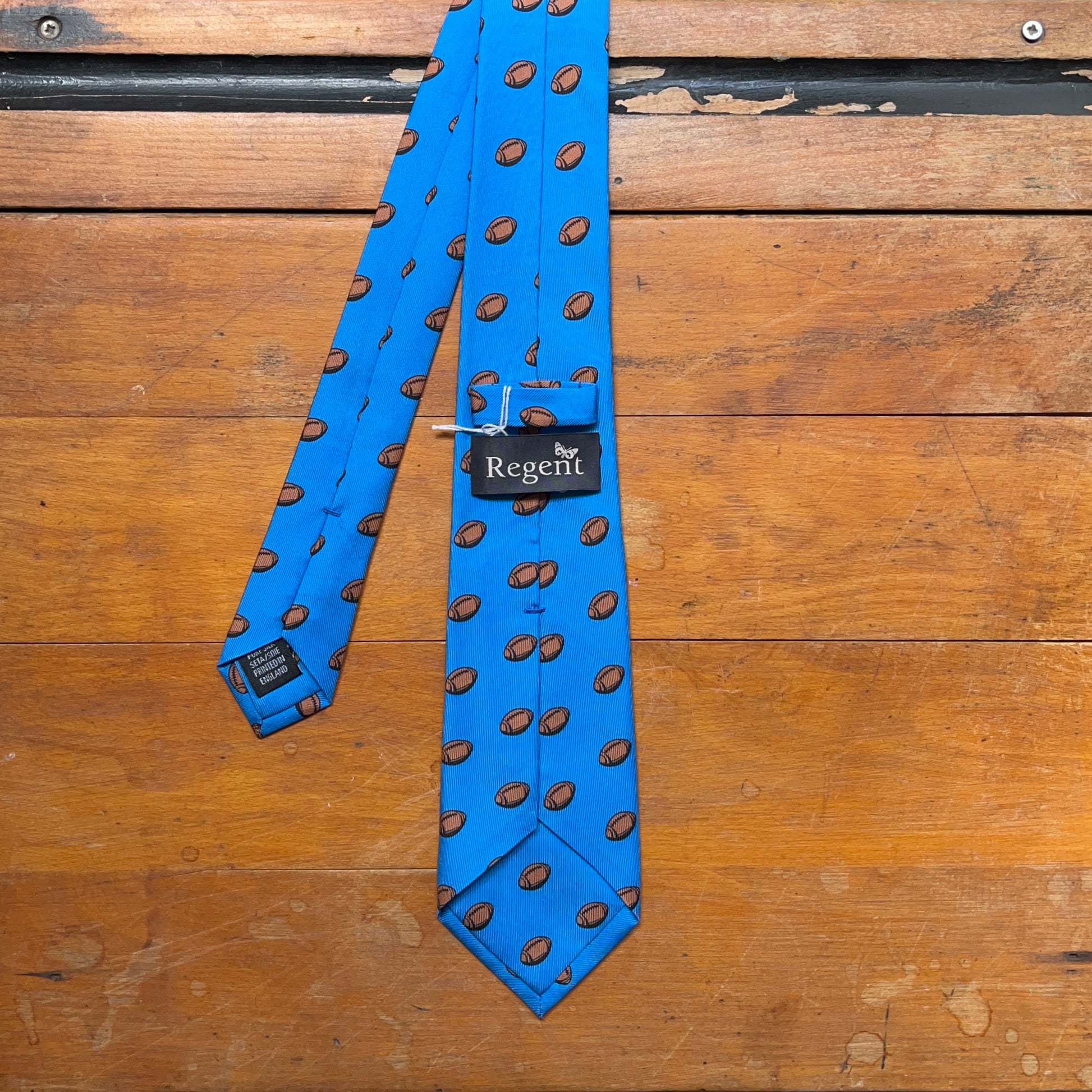 Blue regent tie made from woven silk with rugby ball print pattern - reverse