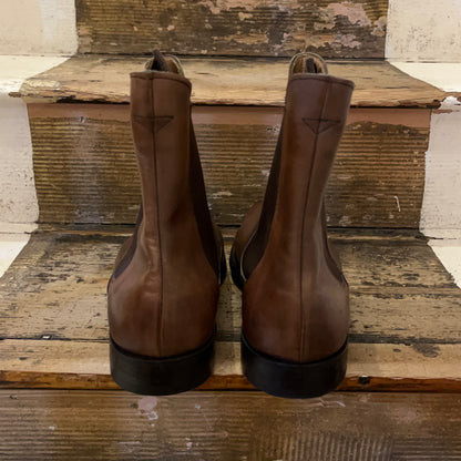 A chelsea boot in espresso coloured leather sitting on some wooden stairs