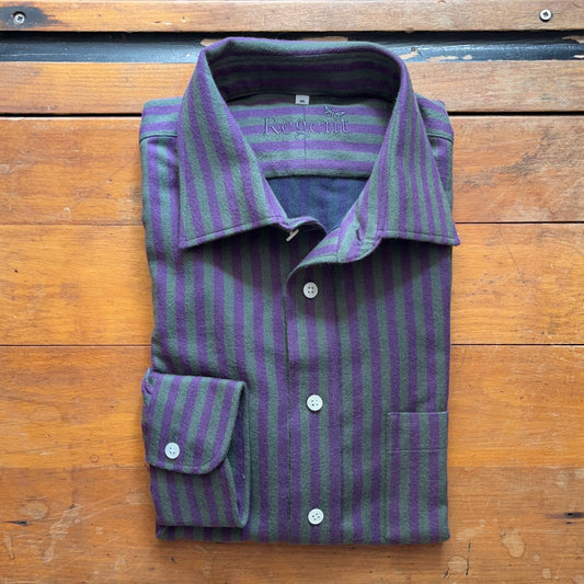 Green and purple flannel shirt folded square sitting on boards of wood