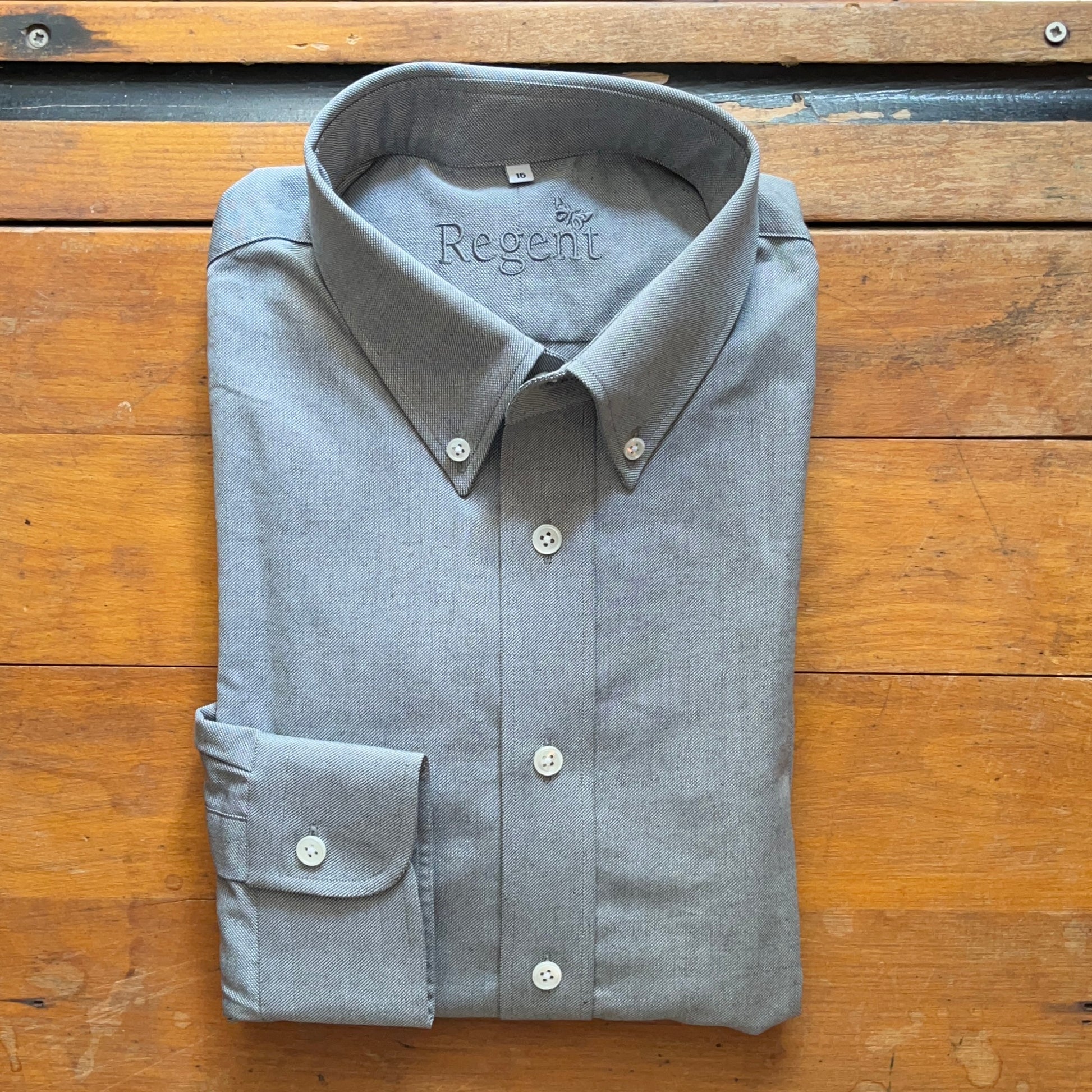 Grey oxford cloth shirt folded square onto wooden boards