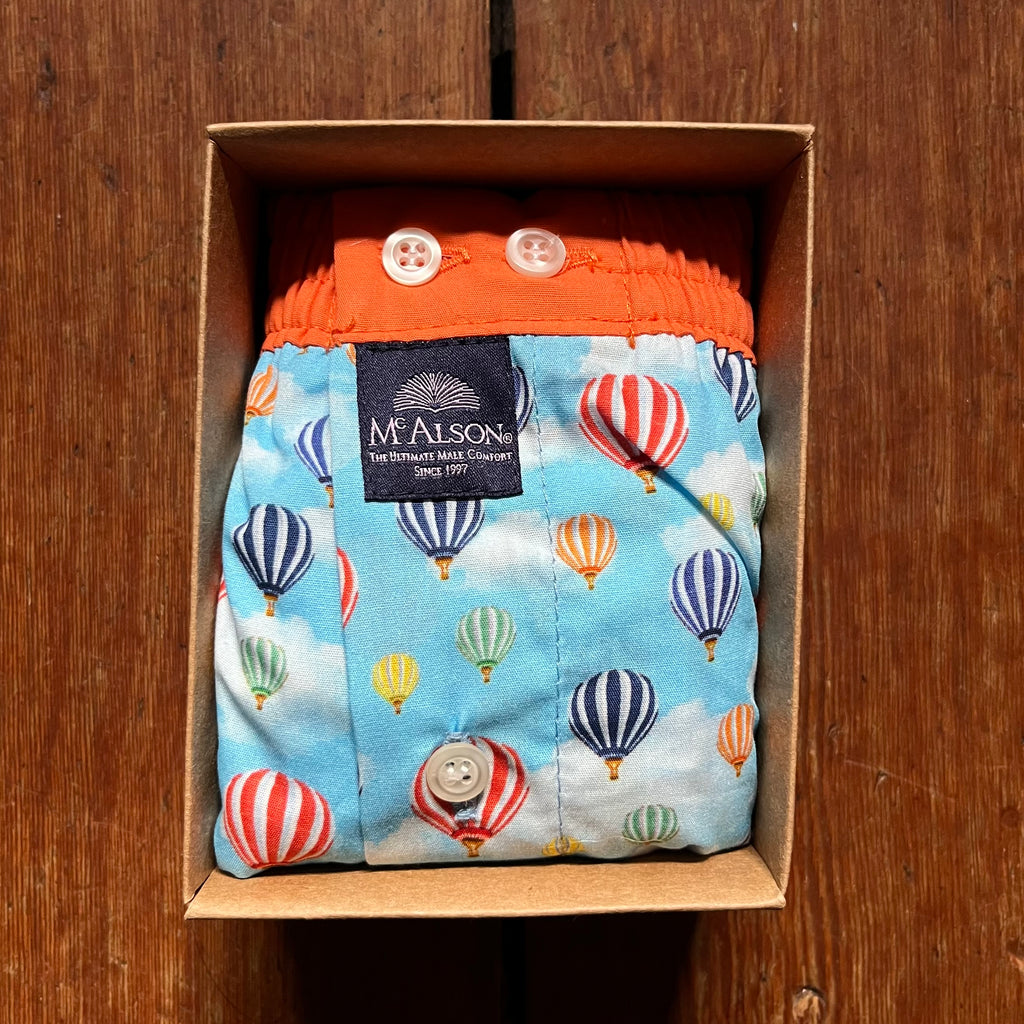 Multicoloured hot air balloons on a cloudy background with a lovely contrasting orange waistband