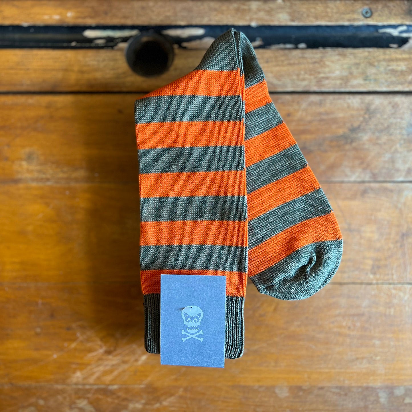 Orange and Kakhi striped hoop socks on a wooden backdrop