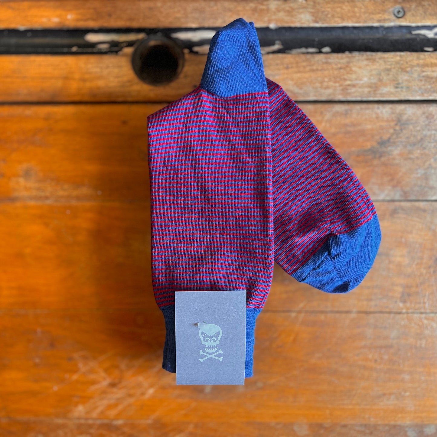 Blue socks with thin red stripes on a wooden backdrop