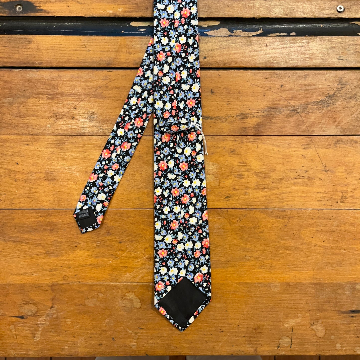 reverse of floral cotton tie on wooden boards