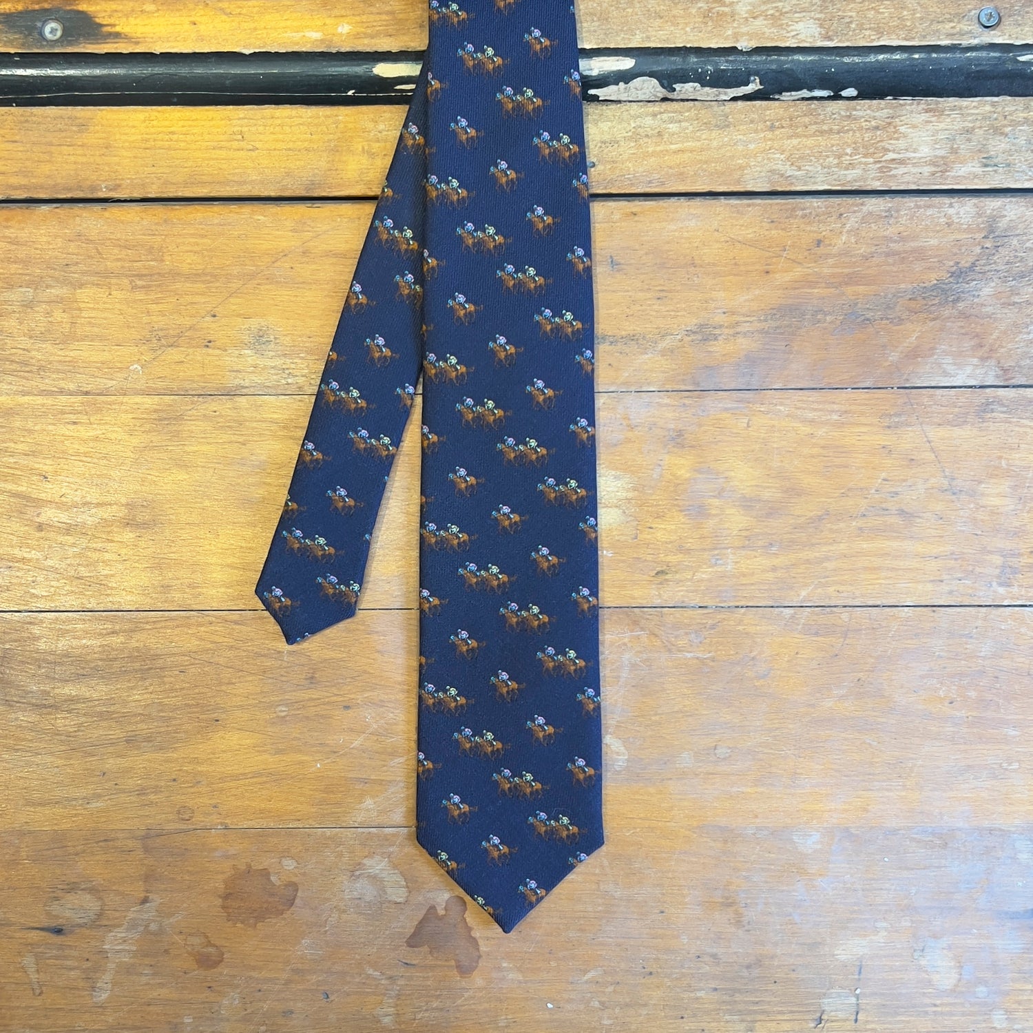 A navy tie with jockeys riding horses