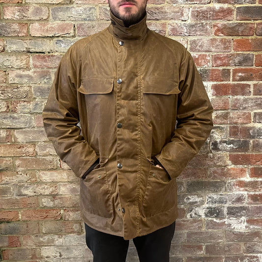 Absolutely stunning bearded man standing against a brick wall in a brown waxed cotton jacket