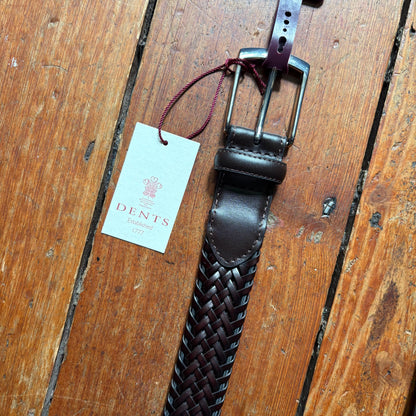Brown leather belt with woven pattern and Dents tag on wooden surface