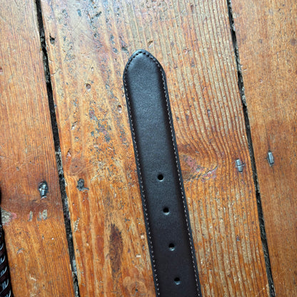 Black leather belt on a wooden surface