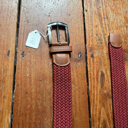 Brown belt with woven red strap on a wooden surface