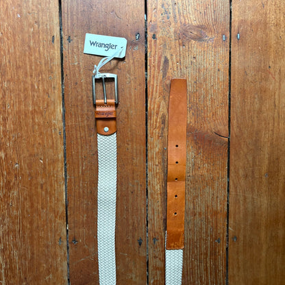 Two belts, one white and one brown, with 'Wrangler' branding on a wooden surface.