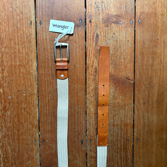 Two belts, one white and one brown, with 'Wrangler' branding on a wooden surface.