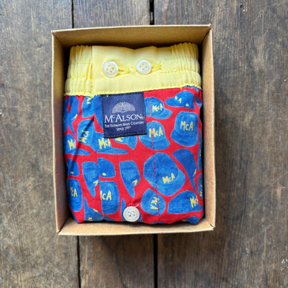 A folded McAlston boxer. The product has a red base with blue abstract shapes and yellow lettering, plus a yellow waistband with white buttons and a dark blue McAlston label.