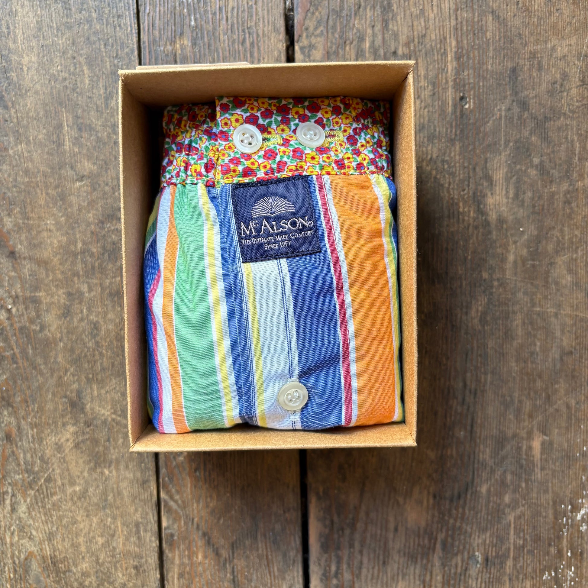 A folded McAlson boxer with colorful vertical stripes and a floral-patterned waistband