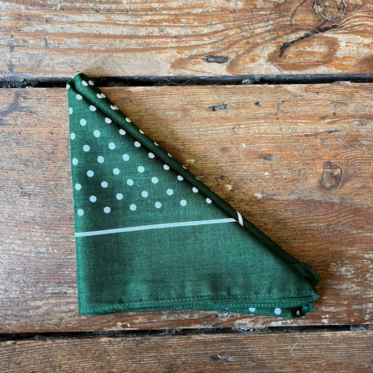 Green fabric with white polka dots on a wooden surface