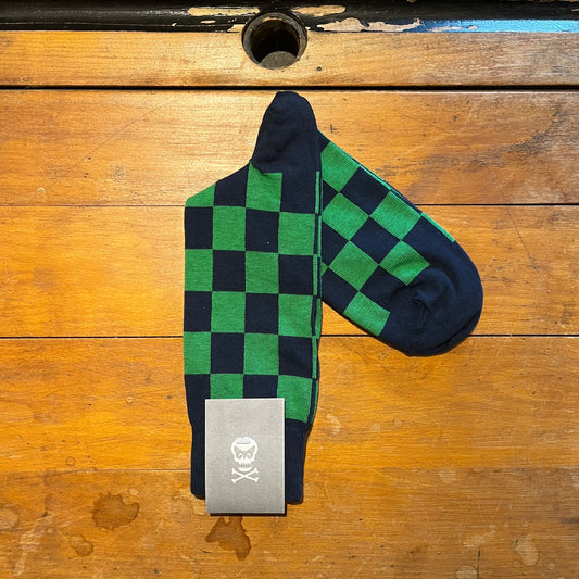 Green and navy checkered socks with a brand label on a wooden surface