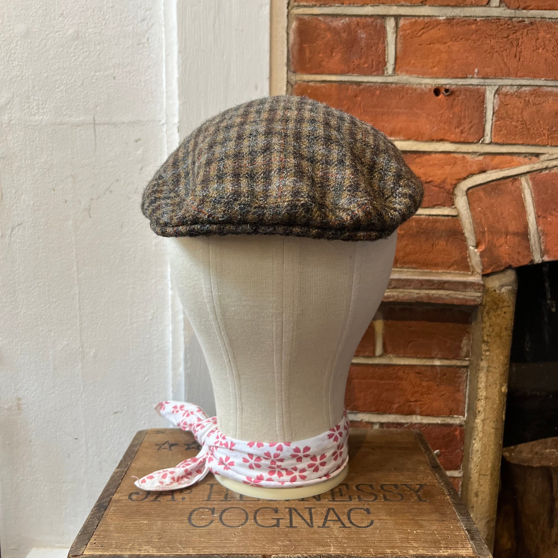 Traditional flat cap in brown tweed checked pattern with orange and grey.