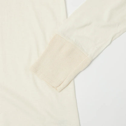 Close-up of a cream-colored sweater with a V-neck on a white background