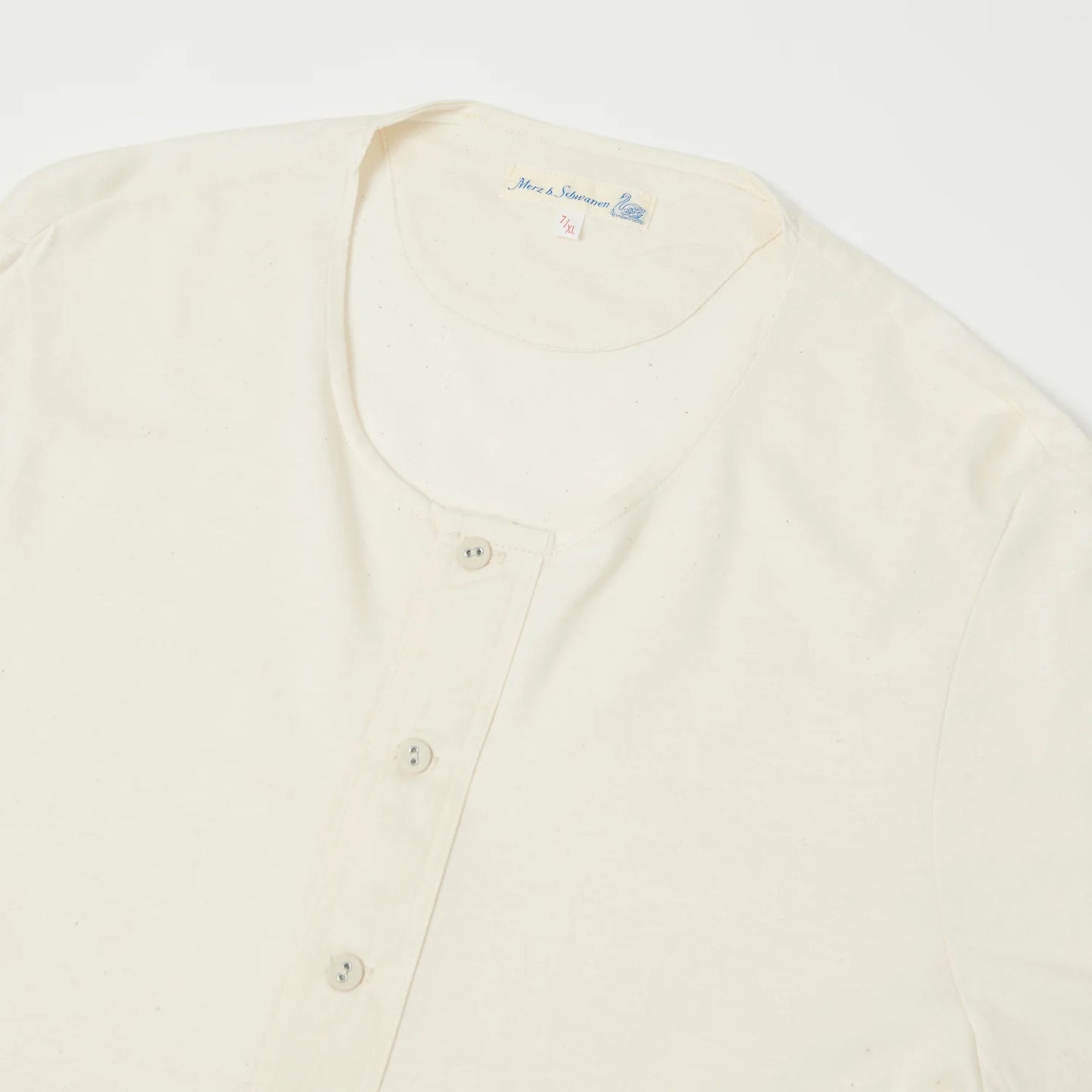 Cream-colored cardigan with button details on a white background