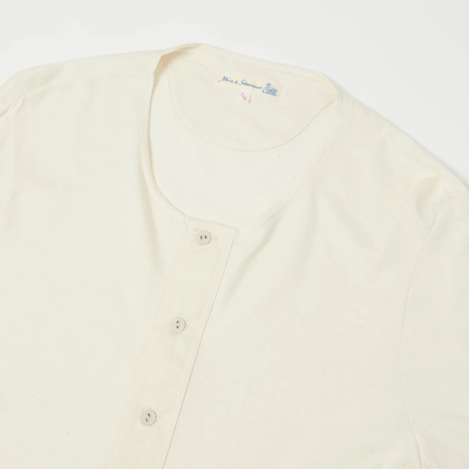 Cream-colored cardigan with button details on a white background