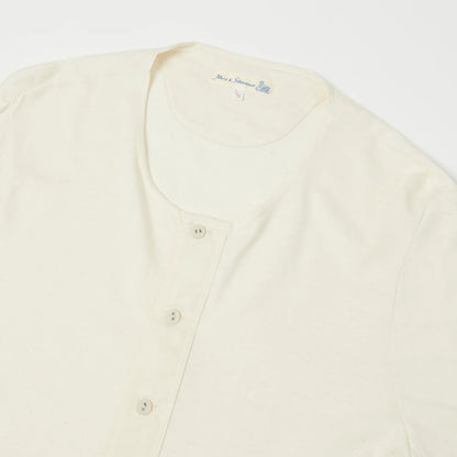 Cream-colored cardigan with button details on a white background