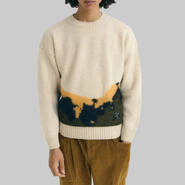 Person wearing a beige sweater with a colorful design on a white background