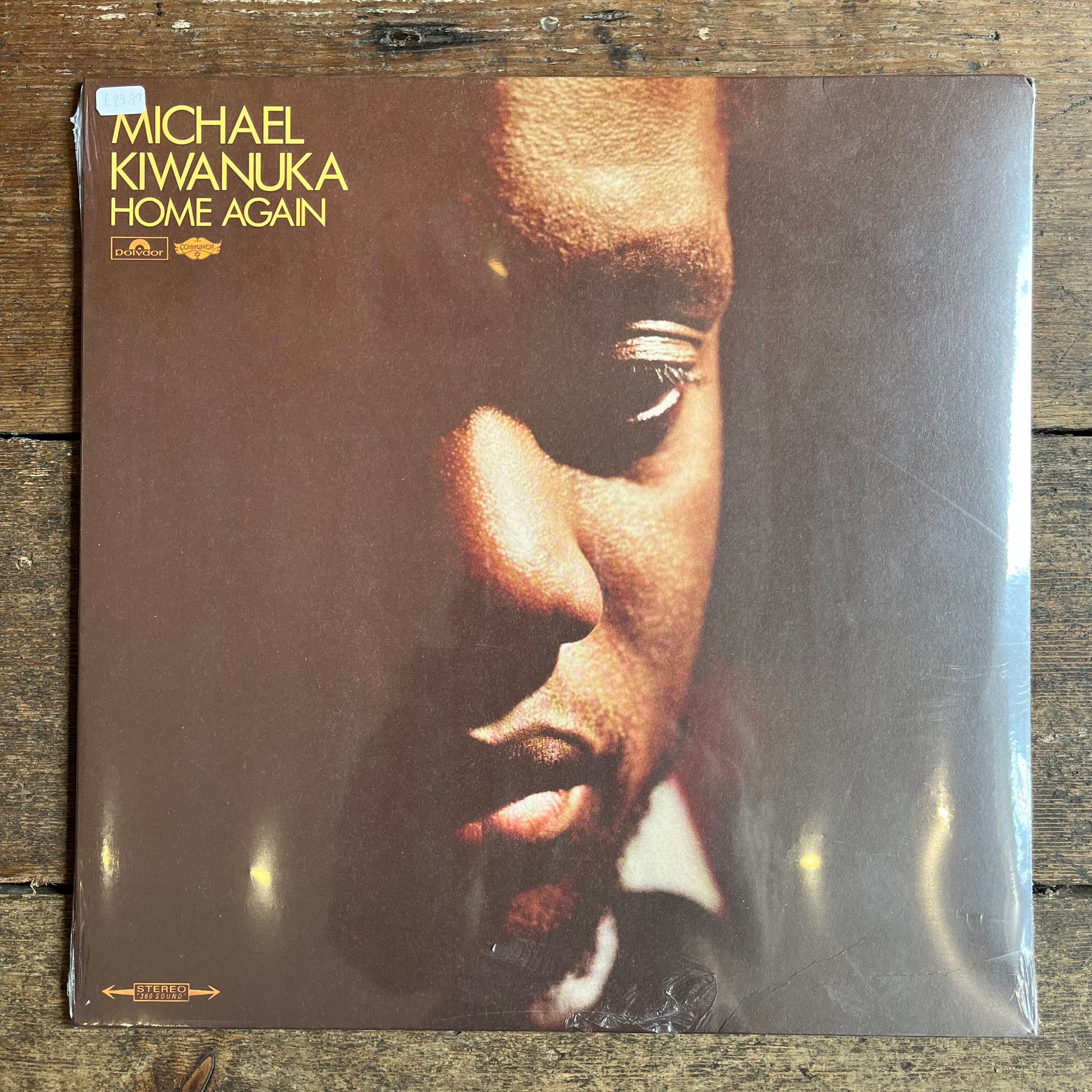 Vinyl record cover of 'Home Again' by Michael Kiwanuka on a wooden surface