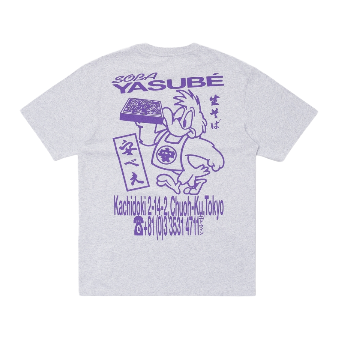 A light gray heather t-shirt showing the back side, which features a purple graphic print of the character Yasubé from The Powerpuff Girls, complete with Japanese text and a stylized address in Tokyo.