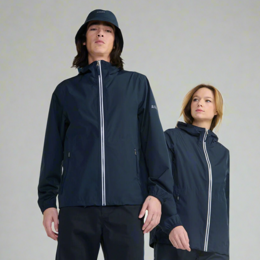 Two people stand wearing rain coats