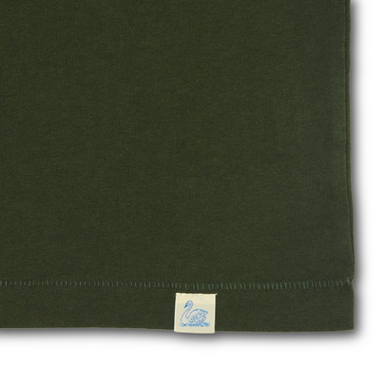 Close-up of a foresr green knit fabric product corner with a small cream fabric tag featuring a blue swan logo near the hem.