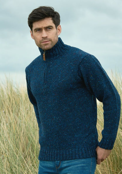 Man wearing a blue knitted sweater standing in a field with a blurred background