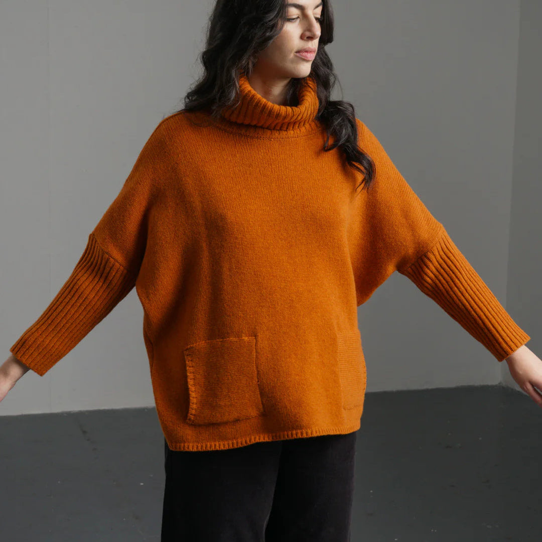 Woman wearing a rust-colored sweater against a gray background