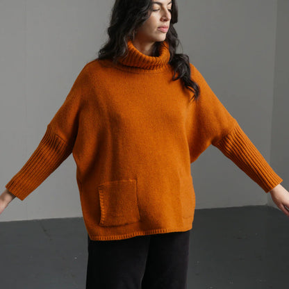 Woman wearing a rust-colored sweater against a gray background