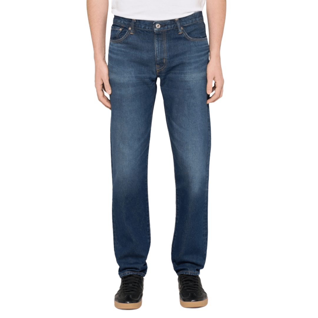 A person wearing a pair of medium blue straight-leg denim jeans with a faded wash.