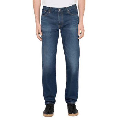 A person wearing a pair of medium blue straight-leg denim jeans with a faded wash.