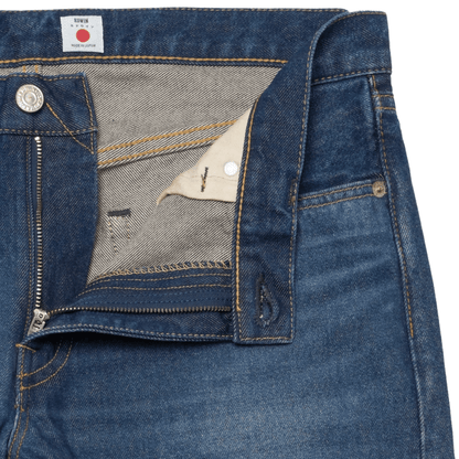 Close-up of dark blue denim jeans showing the inner waistband, zipper fly, and interior lining.