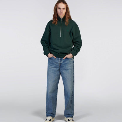 Person wearing a green sweatshirt and blue jeans on a white background