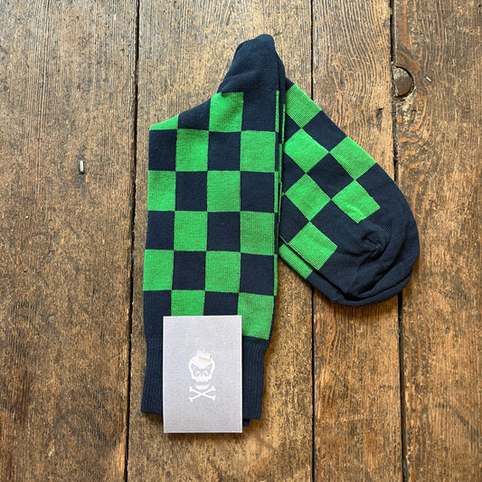 Green and navy checkered socks with a brand label on a wooden surface