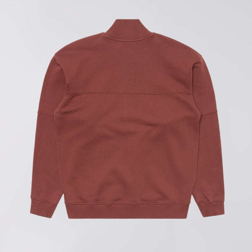 A rust-colored long-sleeve sweatshirt shown from the back, featuring a mock neck collar and ribbed cuffs and hem, photographed against a light gray background.